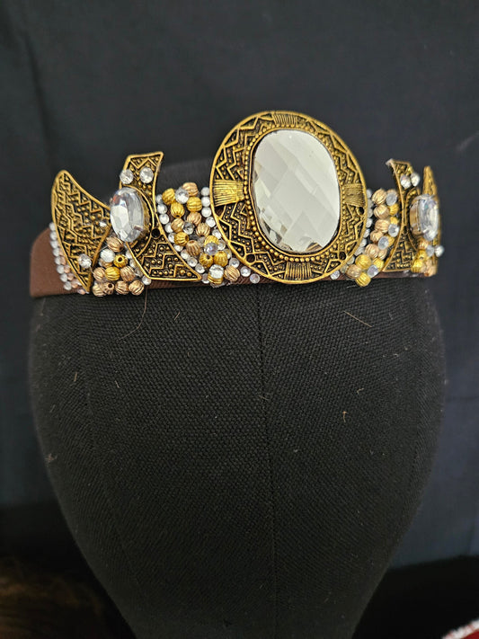 Decorative headband with gold and brown design on a black mannequin head.
