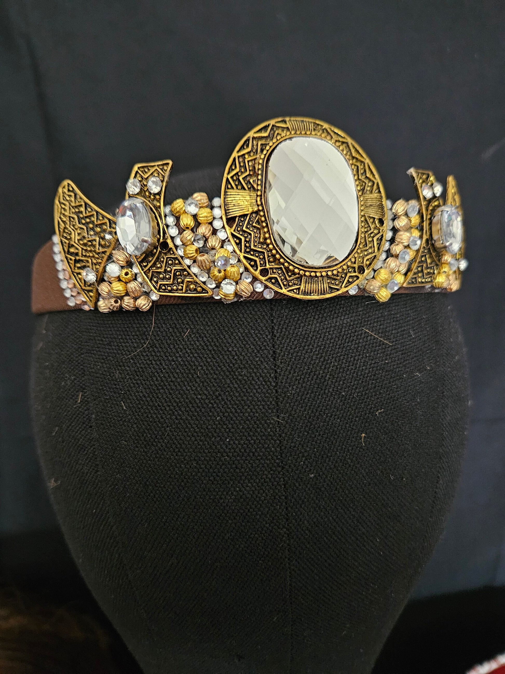 Decorative headband with gold and brown design on a black mannequin head.